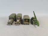 four toy army vehicles are lined up on a white surface