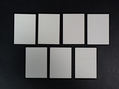 a black wall with six white square tiles on it