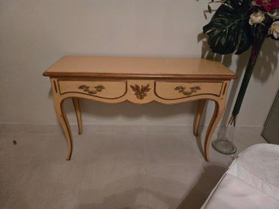 une petite table à deux tiroirs et un vase avec des fleurs