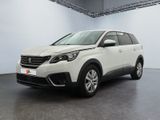 Une voiture blanche est garée dans une pièce blanche au sol noir.