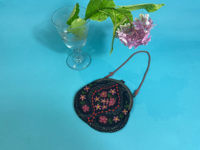 purple and pink flowers in a vase next to a black purse