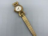 une montre-bracelet en or avec un cadran blanc sur une surface blanche