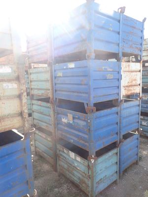 many blue crates stacked on top of each other in the dirt