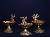 trois bougeoirs en argent ornés d'anges, sur fond bleu
