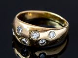 gros plan d'une bague en or avec des diamants sur une surface noire