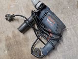 une perceuse filaire posée par terre à côté d'une autre perceuse filaire