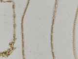 three different types of gold necklaces on a white surface