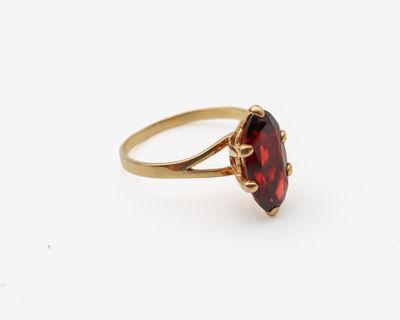 gros plan d'une bague en or avec une pierre rouge