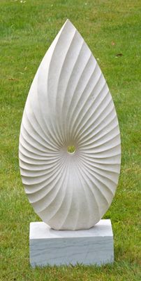 une sculpture blanche posée sur un socle blanc, dans l'herbe