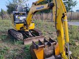 a yellow excavator that is sitting in the grass