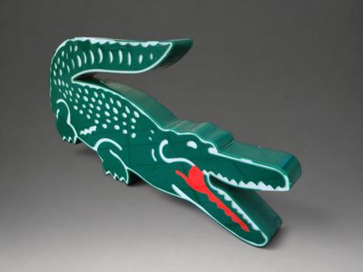 une peluche en forme d'alligator vert avec un nez et une bouche rouges