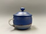une tasse bleue avec un couvercle posée sur une table