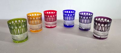 six verres de couleurs différentes sont alignés sur une table