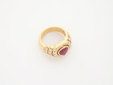 a close up of a gold ring with a red stone and diamonds