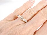 a woman ' s hand with a pearl and diamond ring on it