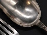 a silver spoon and a fork on a black table