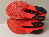 the soles of a pair of red and black shoes on a white surface