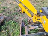 a small yellow excavator that is sitting in the grass