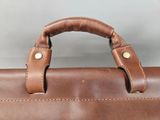 a close up of a brown leather bag with a handle