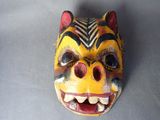 masque jaune et noir avec des yeux et des dents rouges sur un fond gris