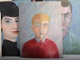 paintings of a man and a woman are on display in front of a wall