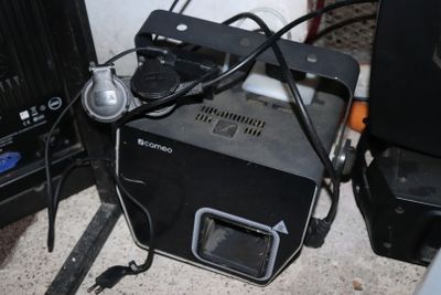 une petite machine noire posée par terre à côté d'autres appareils électroménagers