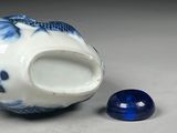 a blue and white vase with a fish on it next to a blue and white stone
