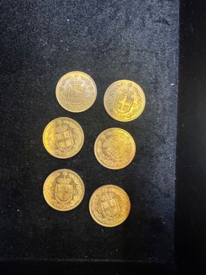 six gold coins in a black box with a black background