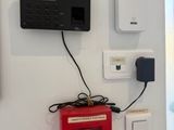 a red fire hydrant sitting on the wall next to a wall mounted clock