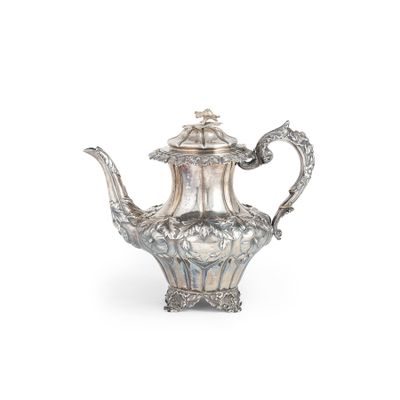 une théière ancienne en argent, ornée de motifs élaborés sur fond blanc