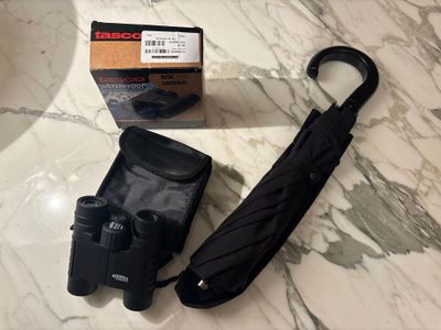 un parapluie noir et un étui noir posés sur une table en marbre