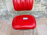 a red chair that is sitting in front of a stone wall