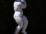 a statue of a child holding a stick in a garden