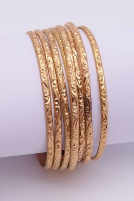 un gros plan sur une pile de bracelets en or posés sur une serviette