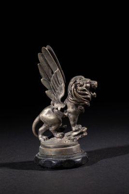 a silver figurine of a winged lion on a rock