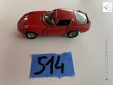 une petite voiture rouge posée à côté d'une feuille de papier bleue