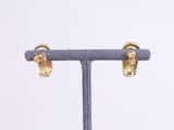 a close up of a pair of gold earrings on a stand