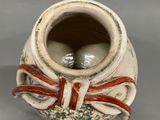 a white vase with a red ribbon and two eggs in it
