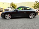 the black porsche 995 is parked in a parking lot
