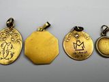 a group of four gold pendants with zodiac signs on them