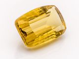 a close up of a yellow sapphire stone on a white surface