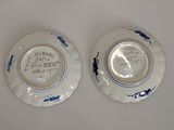 two blue and white plates with writing on them sitting on a table