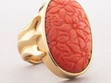 an image of a gold ring with a coral stone in the center
