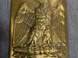 une image représentant une boucle de ceinture en or ornée d'un aigle