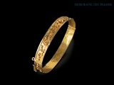 a close up of a gold bracelet on a black background