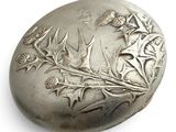 a silver pill case with a design of flowers on it