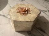 a small box with a flower on it sitting on a marble table