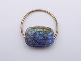 a close up of a gold ring with a blue glass bead on it