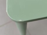 a small green table with a white top on a tiled floor