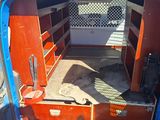 a blue van with a red door and shelves in the back of it